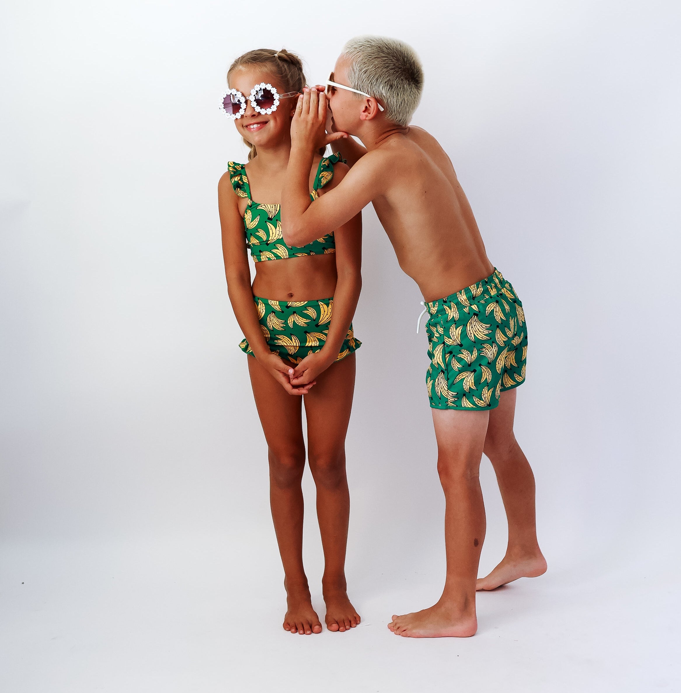 Two children wearing matching BANANA PRINT swimwear on a white background